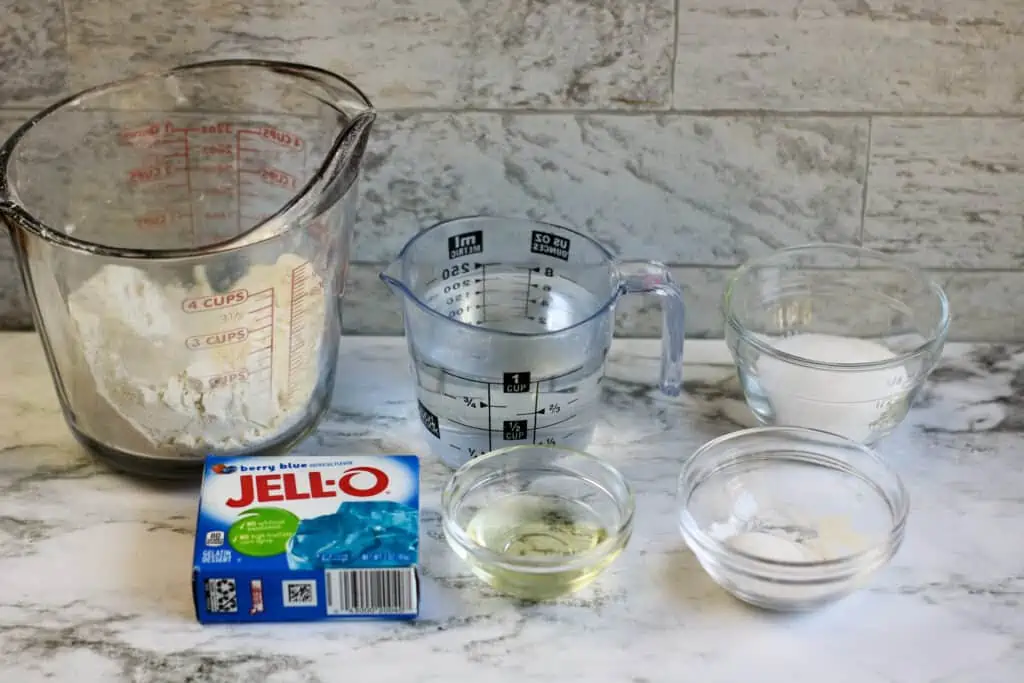 Measuring cups and bowls sitting on a counter filled with ingredients to make Jello Playdough