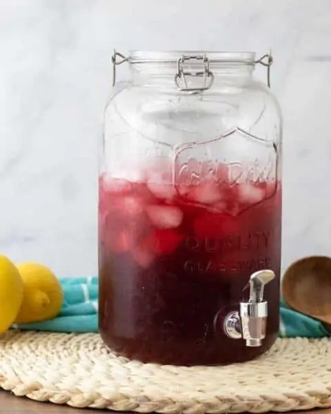 Glassware container full of hibiscus tea with rosehips and lemons.