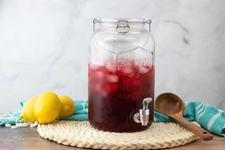 Glassware container full of hibiscus tea with rosehips and lemons.