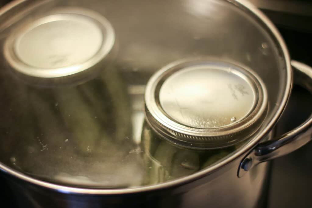 Cucumber jars sealed and in boiling pot of water for canning.