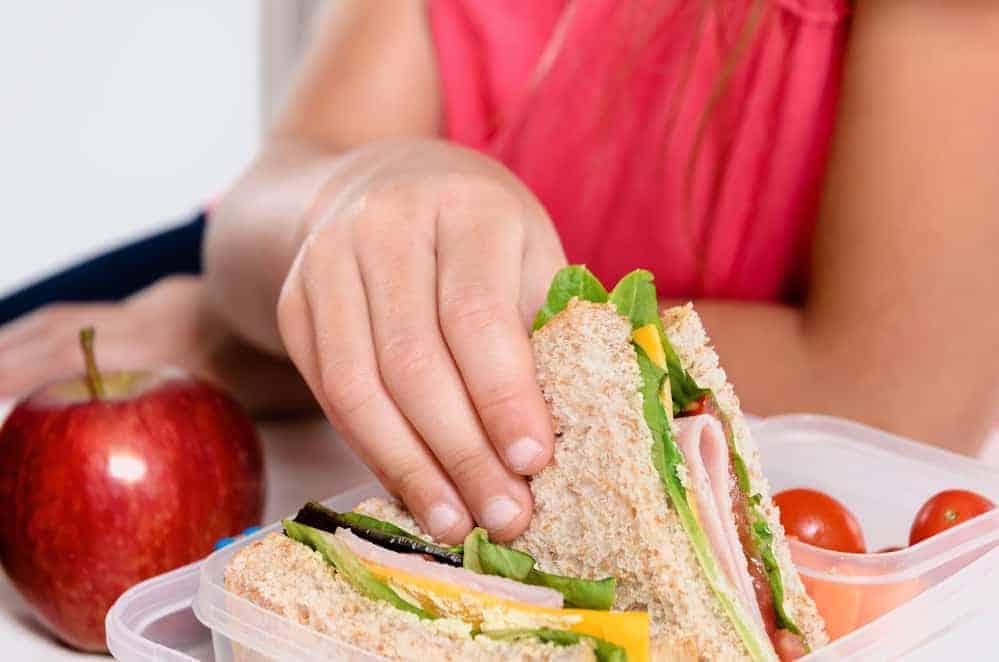 Child removing wholemeal sandwich out of lunchbox