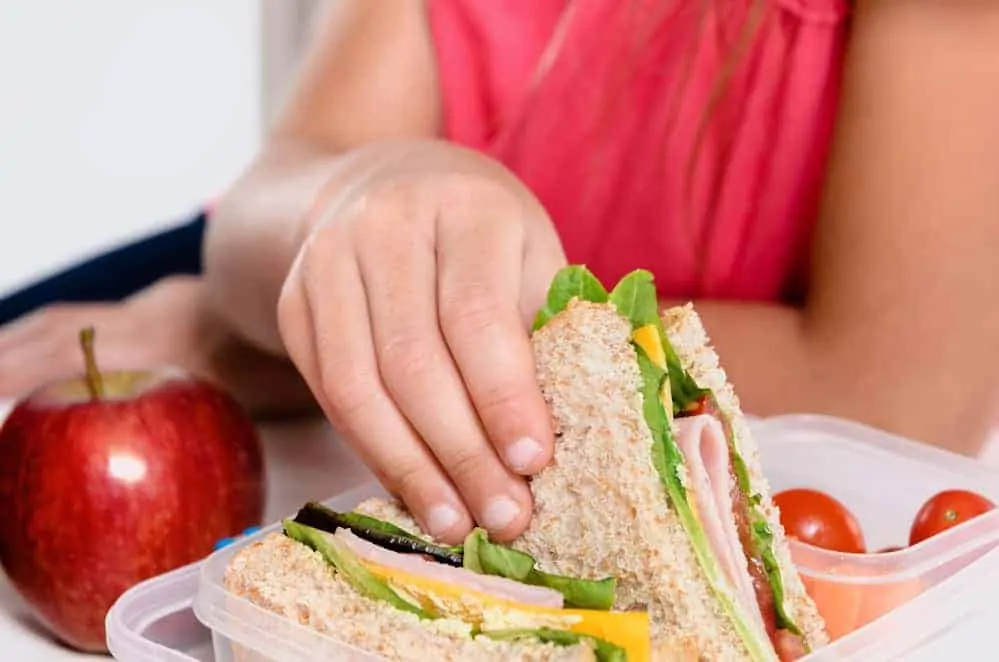 Child removing wholemeal sandwich out of lunchbox