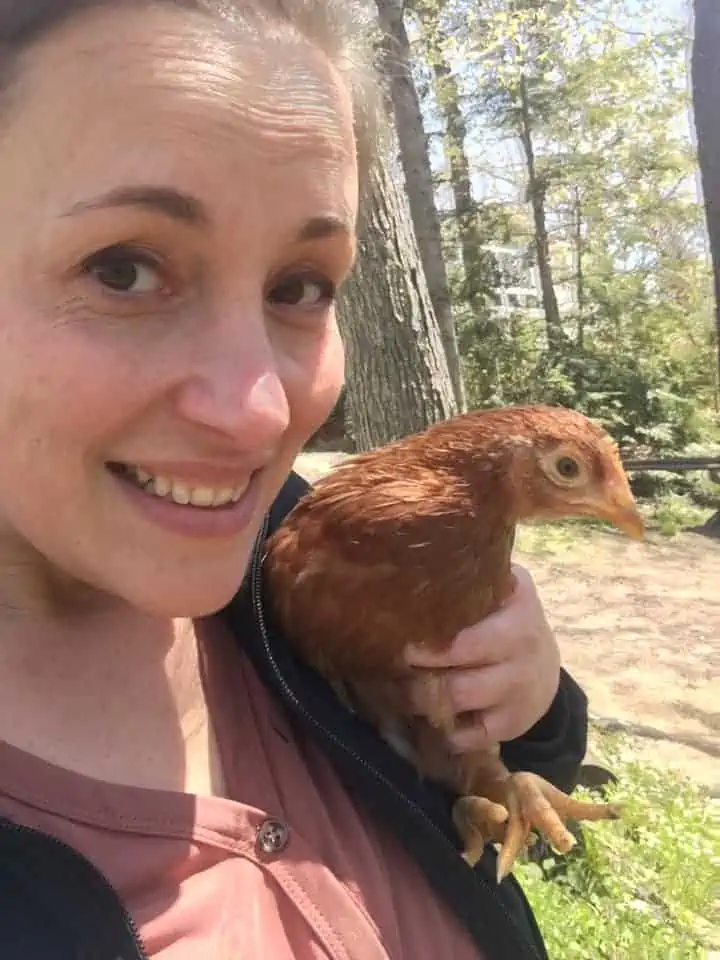 A happy homesteader holding a chicken.
