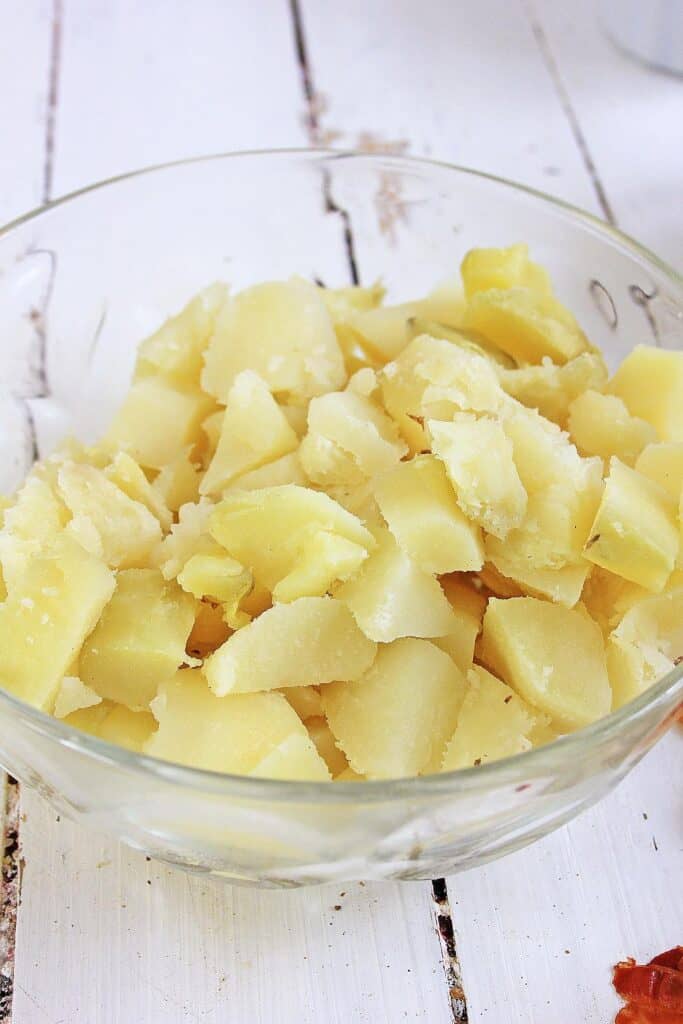 A bowl of cooked, peeled, and cut potatoes. 