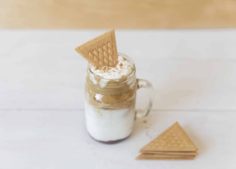 Cookie wafers placed inside pumpkin spice dalgona coffee.