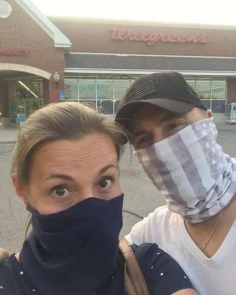 A couple wearing face masks walking into a Walgreens.
