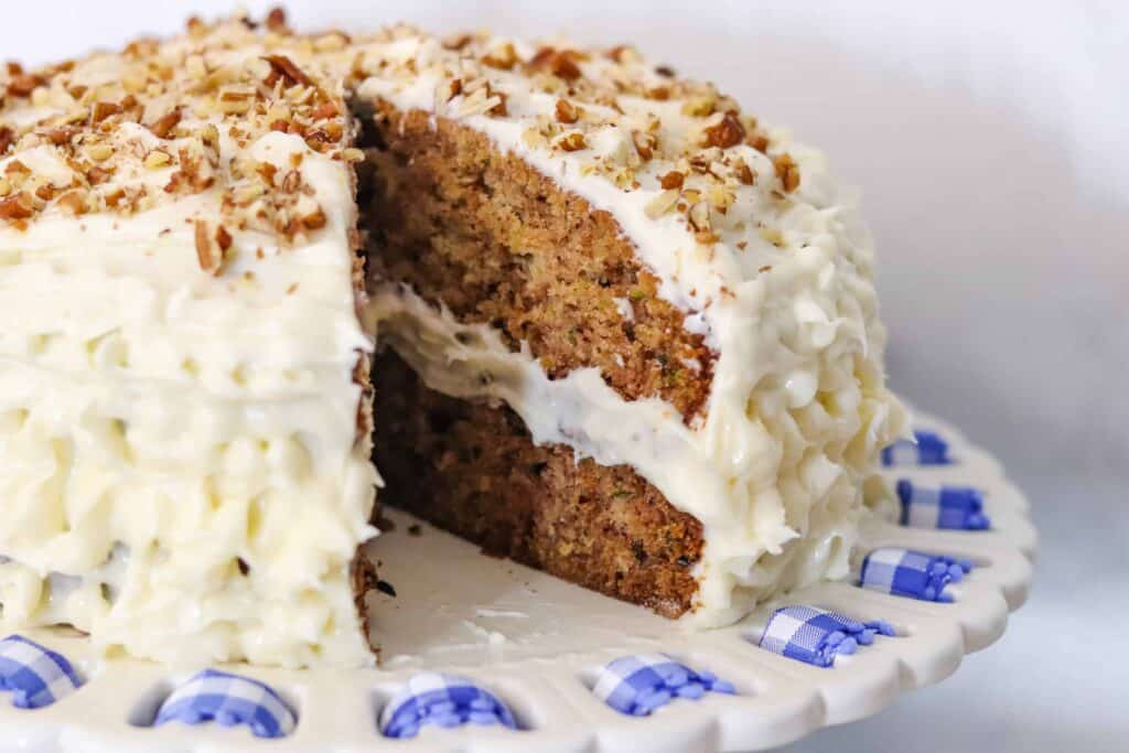Zucchini cake with walnuts sprinkled on top and cream cheese frosting.