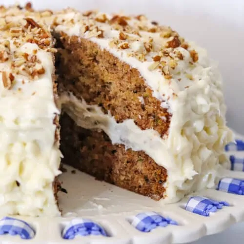 Zucchini cake with walnuts sprinkled on top and cream cheese frosting.
