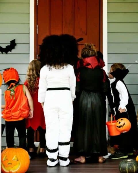 A group of children dressed in their Halloween costumes going trick or treating.