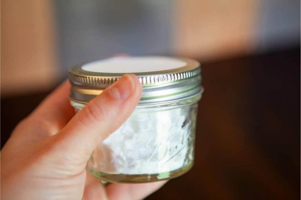 A woman holding a small mason jar of homemade air freshener.