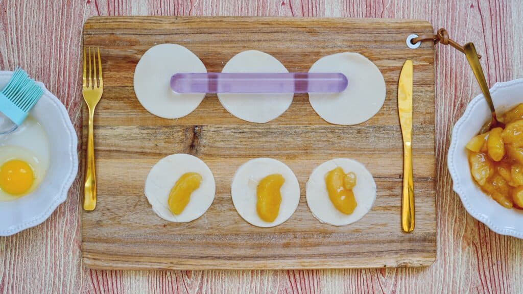 Filling apple pie crust circles with apple pie filling