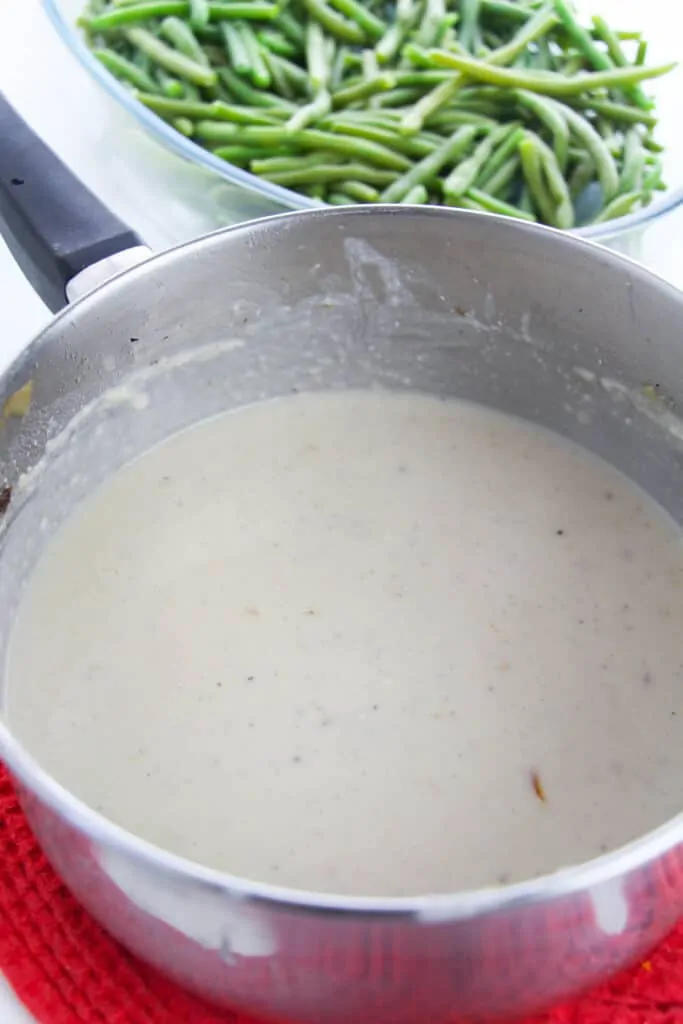 a pan of homemade mushroom soup sitting near a bowl of fresh green beans