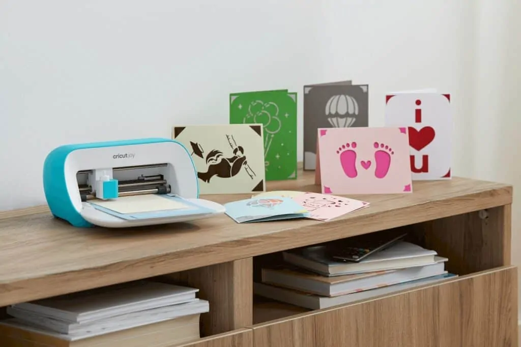 a Cricut machine sitting next to several homemade cards. 