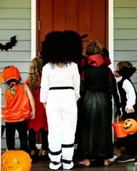A group of kids dressed for Halloween going trick or treating.