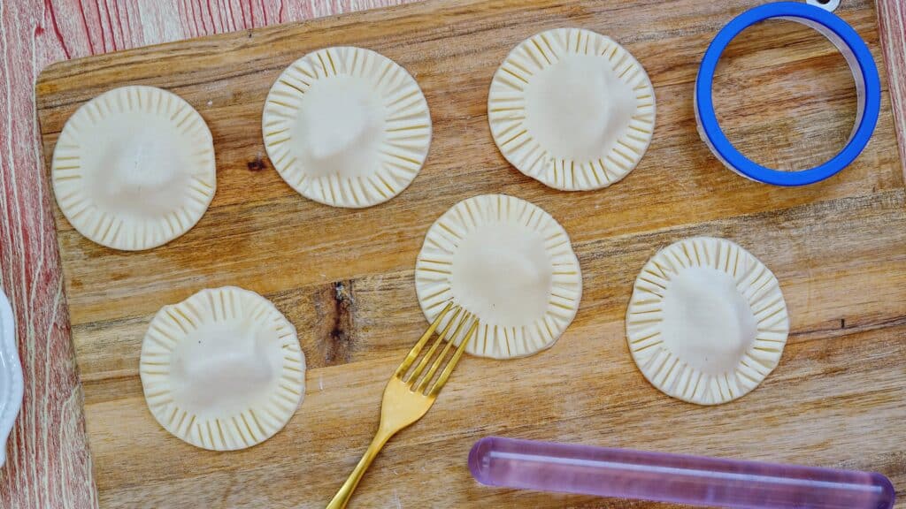 using a fork to combine the top and bottom pieces of a the mini apple pies