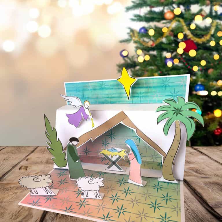 Free printable nativity scene in front of a Christmas tree.