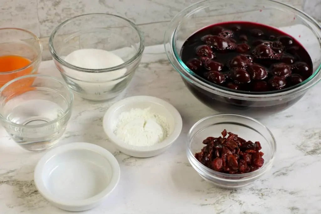 ingredients for the recipe Cherries jubilee sitting in bowls on a countertop.