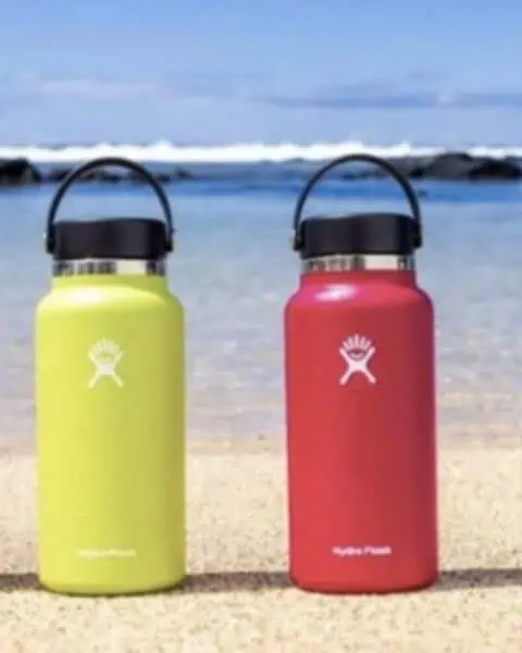 Multi colored Hydro Flasks placed along the beach front.