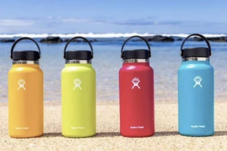 Multi colored Hydro Flasks placed along the beach front.