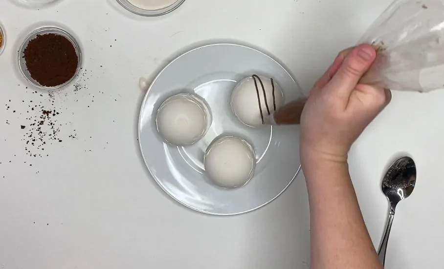 Add chocolate frosting on top of white chocolate cocoa balls.
