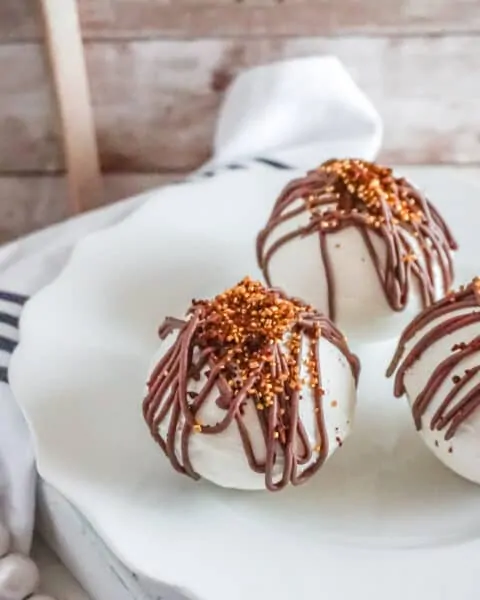 White chocolate mocha hot chocolate balls drizzled with milk chocolate on top.