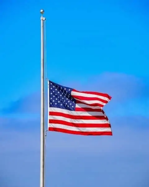 A United States flag at half massed on a flag pole.