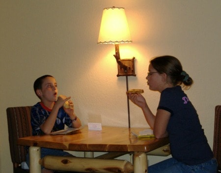 Children sitting at a table and eating food together.