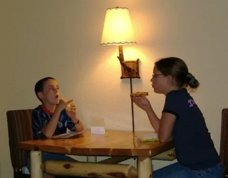 Children sitting at a table and eating food together.