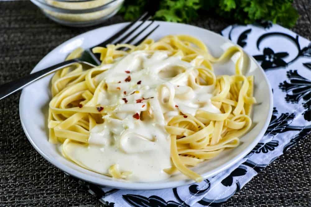 A plateful of pasta covered in creamy alfredo sauce. 
