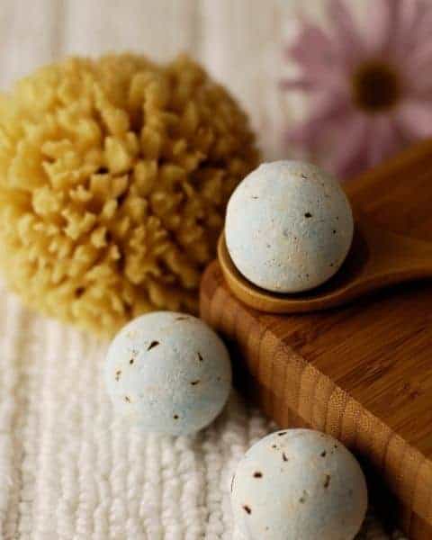 A small group of bath fizzy bombs on a beautiful wooden board and bath sponges. 