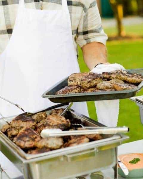 A man working on BBQ outside.