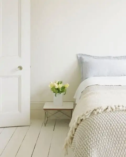 A clean bedroom with fresh flowers next to the bed stand.