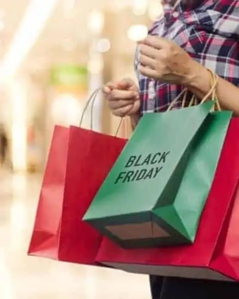 A woman holding several shopping bags with the words "Black Friday" on the outside.