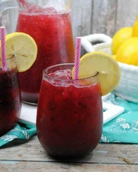 Blackberry lemonade in a glass with a slice of lemon.