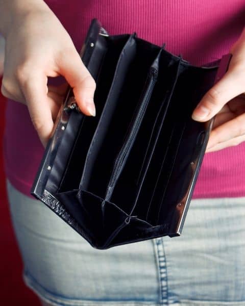 A woman opening up an empty wallet.