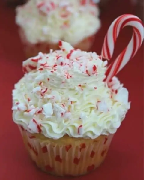 White cupcake with vanilla frosting and candy cane sprinkled on top.