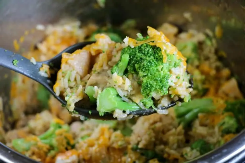 close up of a spoonful of Instant Pot casserole - cheesy broccoli, chicken and rice. 