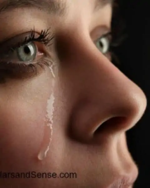 A woman crying with tears running down her cheek.