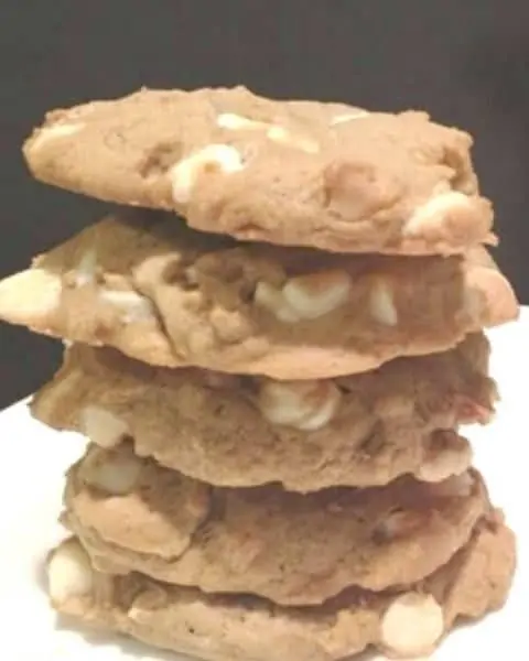 A stack of white chocolate pumpkin cookies with macadamia nuts.