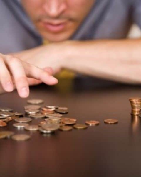 A person stacking penny's, nickels, and other coins.