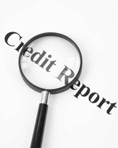 Credit report with magnifying glass on top of words.