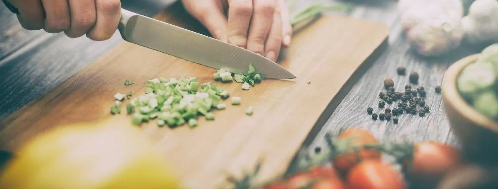 Chef cutting small veggies on a cutting board for an easy dinner.