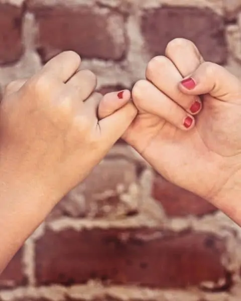 Two people doing a pinky promise.