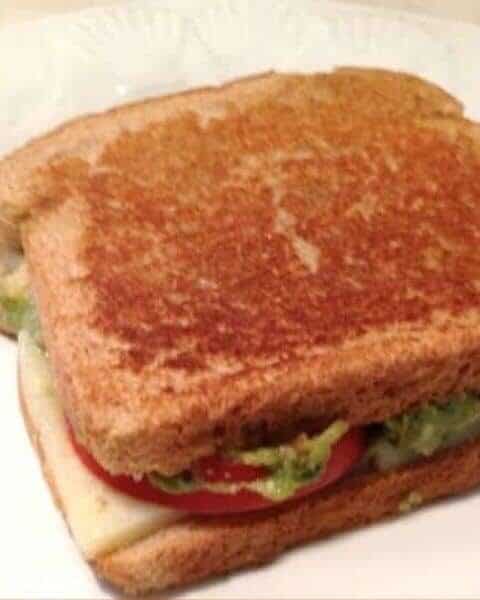 Grilled cheese sandwich with avocado, tomatoes, and cheese.