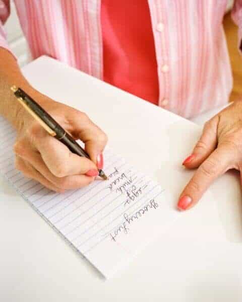 A woman making a list of groceries.