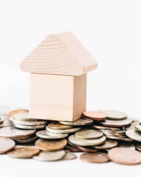 A small wooden house placed on coins.