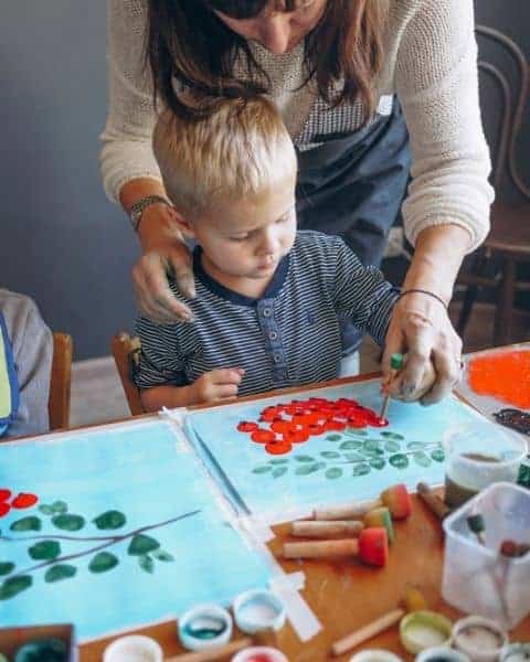A woman helping a small boy with painting.