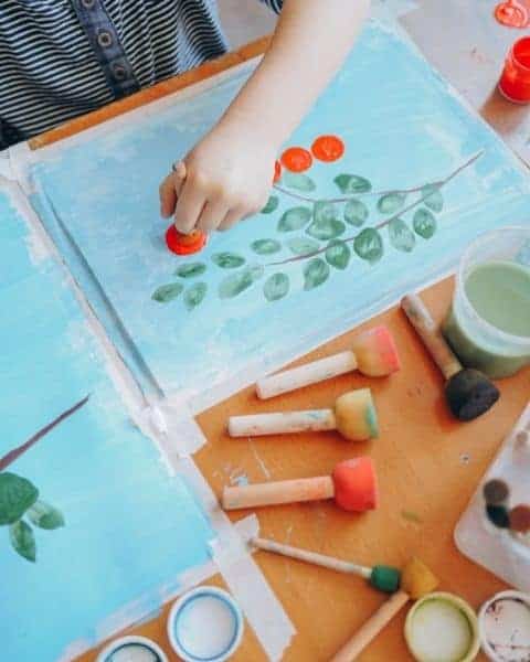 A little girl is painting a picture and learning from home.