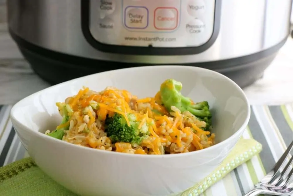 A white bowl full of chicken and broccoli casserole sitting in front of an Instant Pot