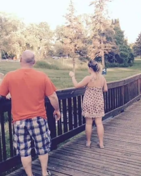 A couple standing on a bridge.